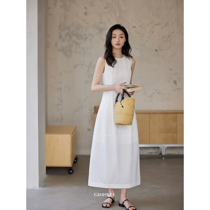 Sleeveless Maxi Dress Paired With a Woven Straw Handbag